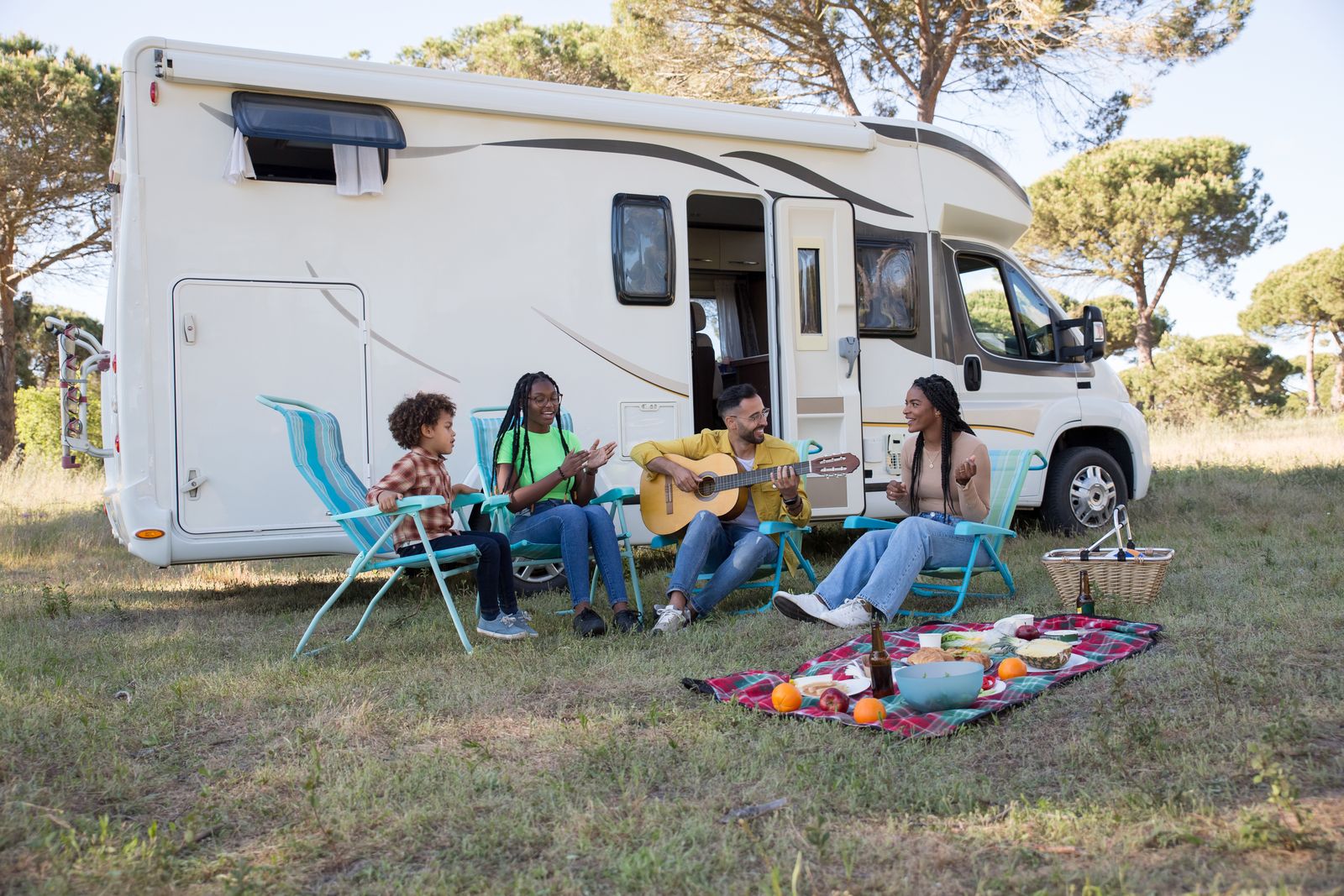 Família tocando violão ao lado de um motorhome